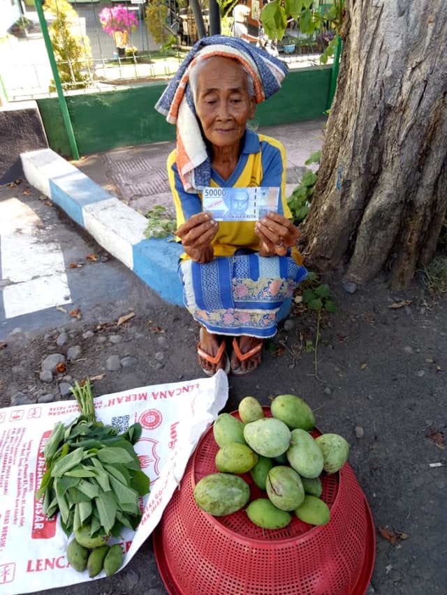 Viral nenek penjual mangga di Bali ditipu seorang pembeli dengan membayar menggunakan uang mainan senilai Rp50 ribu. (Foto: Facebook/Ketut Ajuz)