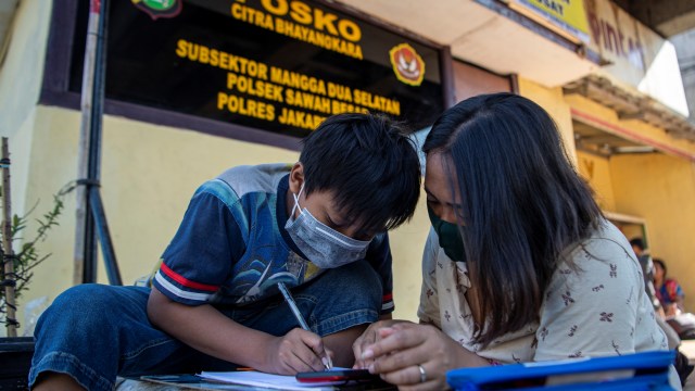 Orang tua siswa membimbing anaknya belajar daring memanfaatkan jaringan internet gratis di kolong rel kereta api Mangga Besar, Jakarta, Rabu (26/8).  Foto: Nova Wahyudi/ANTARA FOTO