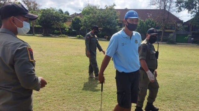 Seorang pria ditegur Satpol PP saat asyik bermain golf di Taman Lumintang, Kota Denpasar, Kamis (27/8). Foto: Satpol PP