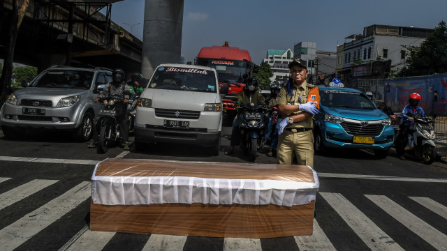 Camat Kecamatan Cilandak Mundari berpose dengan latar depan peti jenazah saat melakukan kampanye bahaya COVID-19 di Jakarta, Senin (31/8/2020). Foto: Muhammad Adimaja/ANTARA FOTO