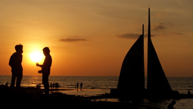 Pengunjung menikmati suasana matahari tenggelam di Pantai Tanjung Layar Putih, Makassar, Sulawesi Selatan, Minggu (30/8/2020) Foto:  YUSRAN UCCANG/ANTARA FOTO