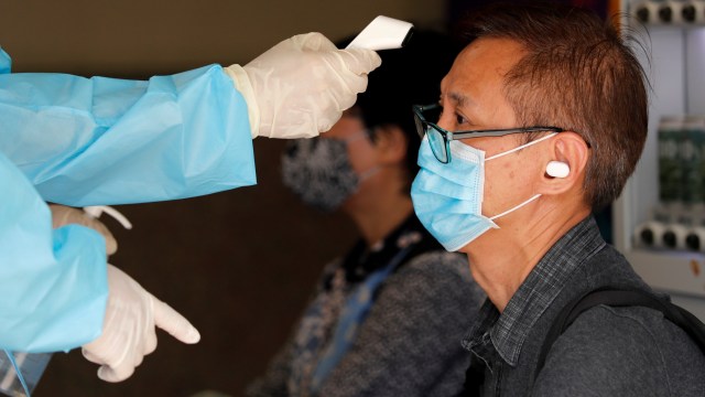Seorang pria diperiksa suhu tubuhnya sebelum tes virus corona di pusat pengujian virus corona, Hong Kong. Foto: Tyrone Siu/REUTERS