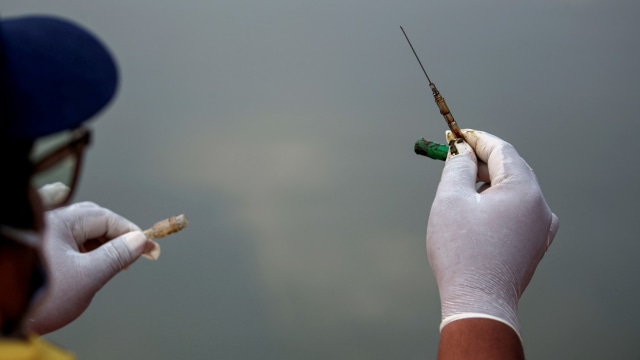 Ade Yunus, pendiri kelompok lingkungan Bank Sampah Sungai Cisadane (Banksa Suci), memegang jarum suntik yang dibuang saat dia mengumpulkan limbah medis di sungai Cisadane di Tangerang, Banten. Foto: WILLY KURNIAWAN/REUTERS