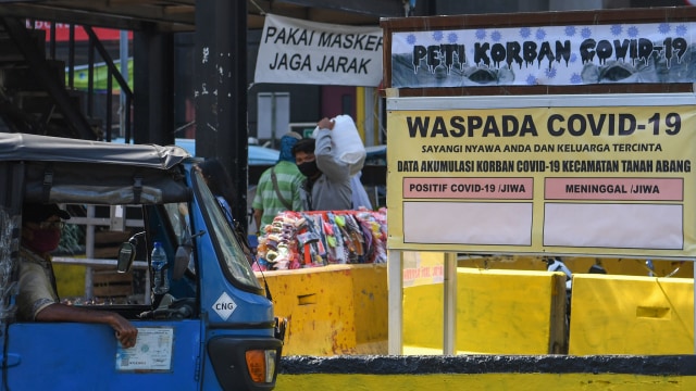 Warga melintasi replika peti mati dan papan himbauan waspada COVID-19 di kawasan Pasar Tanah Abang, Jakarta, Selasa (1/9/2020). Foto: Wahyu Putro A /ANTARA FOTO