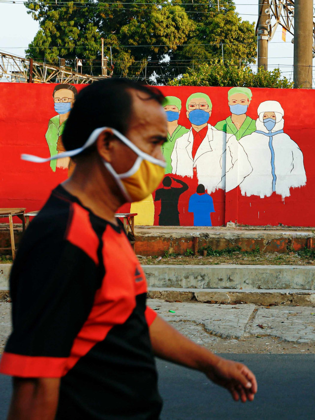 Warga melewati mural yang berisi pesan waspada penyebaran virus Corona di kawasan Tebet, Jakarta. Foto: Ajeng Dinar Ulfiana/Reuters