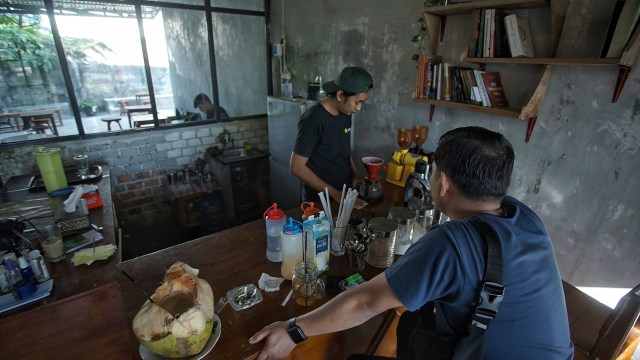 Seorang pengunjung kedai kopi lawas yang tengah menunggu pesanan kopi, Selasa (1/9) Foto: ary priyanto/Urban Id