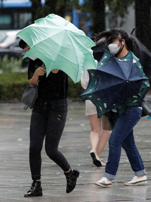 Orang-orang berjuang dengan payung mereka melawan angin kencang dan hujan di pusat kota Seoul, Korea Selatan, Kamis (3/9). Foto: Lee Jin-man/AP Photo