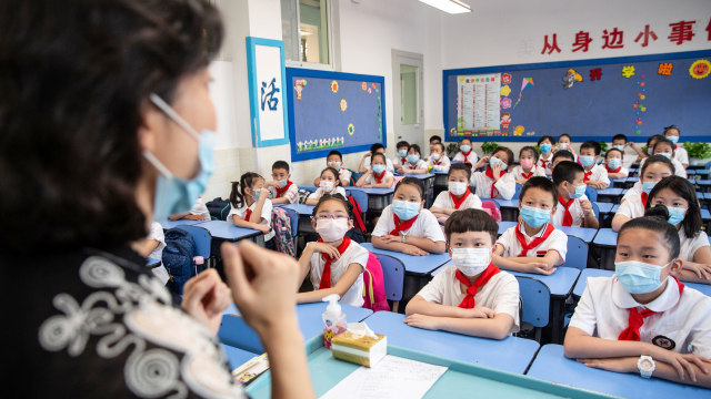 Sejumlah siswa sekolah dasar menghadiri kelas pada hari pertama semester baru di Wuhan, Hubei, China, Selasa (1/9). Foto: STR/AFP