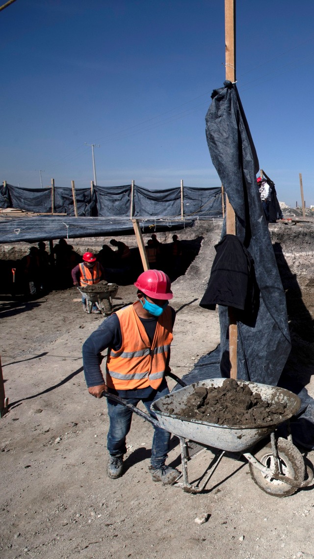 Pekerja mengeluarkan gerobak dirs saat ahli paleontologi bekerja mengawetkan kerangka mammoth yang ditemukan di lokasi pembangunan bandara baru Mexico City di pangkalan militer Santa Lucia, Meksiko, Kamis (3/9). Foto: Marco Ugarte/AP Photo