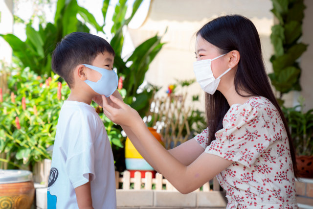 Ilustrasi ibu memakaikan masker kepada anak Foto: Shutterstock