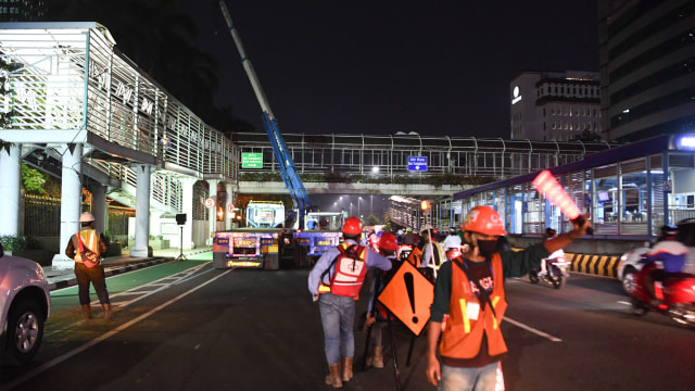 Petugas mengatur laju lalu lintas saat menyiapkan alat berat untuk membongkar Jembatan Penyeberangan Orang (JPO) halte Transjakarta Bank Indonesia di Jalan MH Thamrin, Jakarta, Sabtu (5/9/2020) dini hari. Foto: Hafidz Mubarak A/ANTARA FOTO