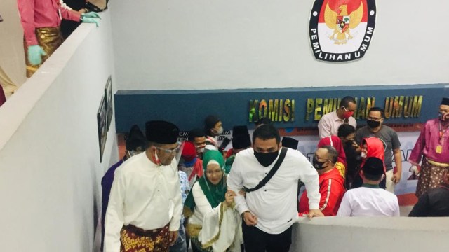 BAKAL Calon Wakil Bupati Bengkalis, Sri Barat atau dikenal Iyeth Bustami, memegang tangan suaminya saat menaiki anak tangga di kantor KPU ketika mendaftar.