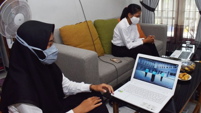 Dua orang mahasiswi baru Universitas Gadjah Mada (UGM) Yogyakarta mengikuti Orientasi Studi dan Pengenalan Kampus (Opspek) secara daring di rumahnya di Kota Madiun, Jawa Timur, Senin (7/9). Foto: Siswowidodo/ANTARA FOTO