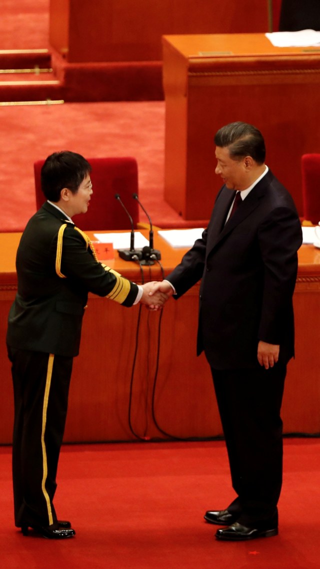 Presiden Tiongkok Xi Jinping berjabat tangan dengan dengan peneliti vaksin dan mayor Jenderal Tentara Pembebasan Rakyat (PLA) Chen Wei. Foto: Carlos Garcia Rawlins/REUTERS