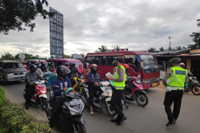 Petugas Satlantas Polda Kepri membagikan masker kepada para pengendara. Foto: Rega//kepripedia.com