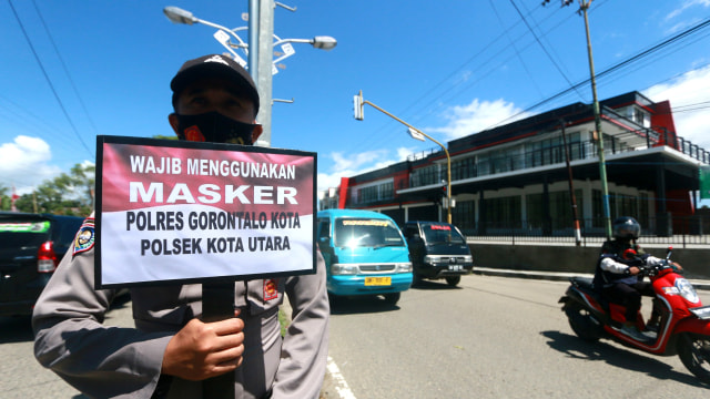 Petugas kepolisian memegang papan imbauan saat Operasi Yustisi penerapan protokol kesehatan di Jalan Jhon Aryo Katili di Kota Gorontalo, Gorontalo, Senin (14/9).  Foto: Adiwinata Solihin/ANTARA FOTO