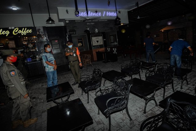 Anggota Satpol PP memberi peringatan terhadap pemilik usaha untuk tidak menyediakan makan di tempat saat razia penerapan Pembatasan Sosial Berskala Besar (PSBB) total di kawasan Bendungan Hilir, Jakarta, Senin (14/9/2020) malam. Foto: SIGID KURNIAWAN/ANTARA FOTO