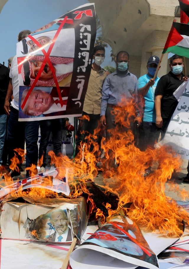 Warga Palestina membakar gambar Presiden AS Donald Trump, Raja Bahrain Hamad bin Isa Al Khalifa, dan Perdana Menteri Israel Benjamin Netanyahu saat aksi protes di Kota Gaza, (15/9). Foto: Mohammed Salem/REUTERS