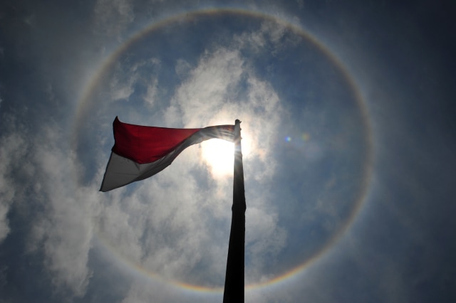 Bendera merah putih berkibar saat terjadinya Halo Matahari di Kayu Aro Barat, Kerinci, Jambi, Jumat (28/8/2020). Foto: Wahdi Septiawan/ANTARA FOTO