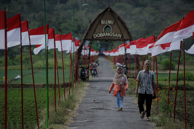 Warga berjalan di antara deretan benera merah putih yang dipasang di kawasan Dobangsan, Giripeni, Wates, Kulon Progo, D.I Yogyakarta, Rabu (19/8/2020). Foto: Andreas Fitri Atmoko/ANTARA FOTO