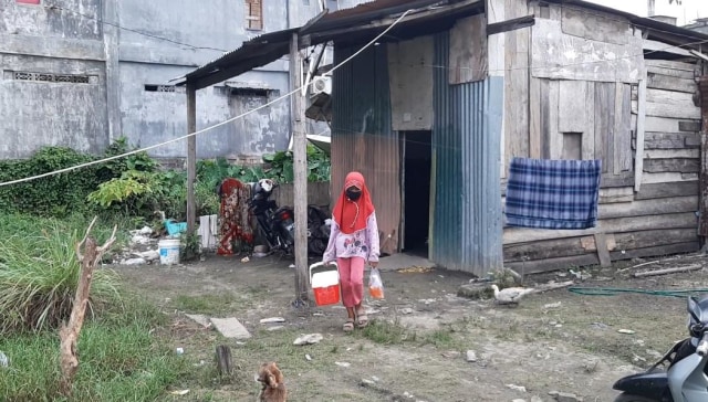 Asisah saat akan berangkat menjajakan gorengan hasil olahan ibunya. Tampak belakang rumah tempat Asisah tinggal bersama kedua orang tuanya. Foto: Lukman Budianto/kendarinesia.