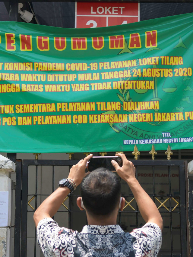 Warga memotret pengumuman pelayanan di Kantor Kejaksaan Negeri (Kejari) Jakarta Pusat yang tutup sementara di Jakarta, Jumat (18/9/2020). Foto: Galih Pradipta/kumparan