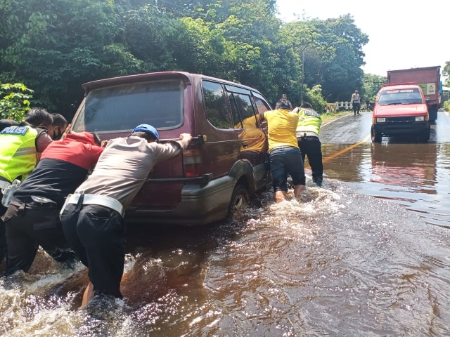 Anggota Satlantas membantu pengendara mobil yang mogok di ruas jalan yang tergenang banjir. (Foto: Dokumen Iptu Suwaris)