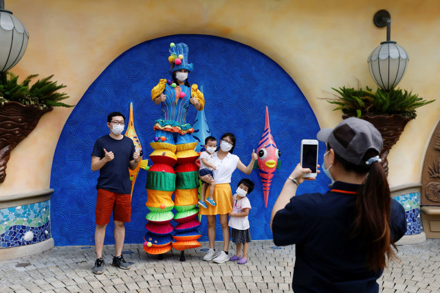 Wisatawan berfoto di taman hiburan ikonik Ocean Park, di Hong Kong. Foto: Tyrone Siu/Reuters