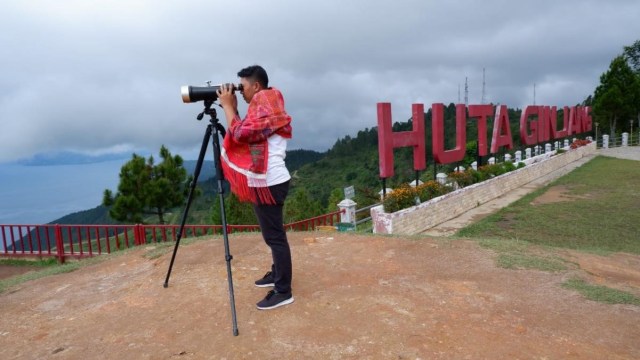Wisatawan melihat pemandangan Danau Toba dari Huta Ginjang, Tapanuli Utara.