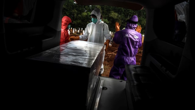 Petugas penggali makam jenazah COVID-19 bersiap menurunkan peti di komplek pemakaman Pondok Ranggon. Foto: Muhammad Adimaja/ANTARA FOTO