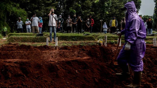 Petugas penggali makam menunggu kerabat jenazah korban COVID-19 mengumandangkan adzan di komplek pemakaman Pondok Ranggon. Foto: Muhammad Adimaja/ANTARA FOTO