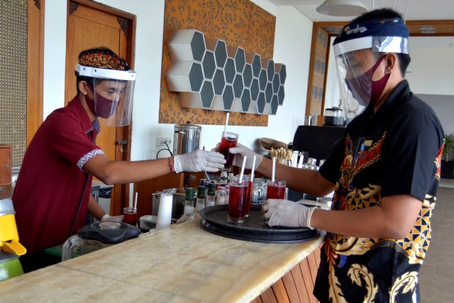 Pekerja mengenakan alat pelindung wajah saat menyiapkan minuman di restoran hotel sesuai ketentuan sertifikasi fasilitas wisata di Nusa Dua. Foto: Fikri Yusuf/ANTARA FOTO