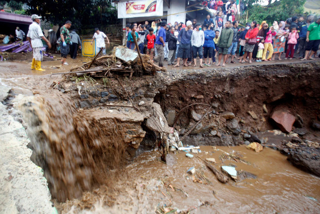 Warga melihat jalanan yang rusak pasca banjir bandang di Kampung Cibuntu, Desa Pasawahan, Kecamatan Cicurug, Sukabumi, Jawa Barat. Foto: Yulius Satria Wijaya/Antara Foto