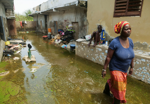 Warga berada di gang rumah mereka yang banjir setelah hujan lebat di distrik Yeumbeul di pinggiran Dakar, Senegal. Foto: CHRISTOPHE VAN DER PERRE/REUTERS