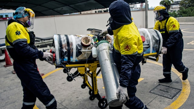 Petugas membawa pasien COVID-19 dalam kapsul evakuasi saat tiba di Unit Perawatan Intensif Rumah Sakit Rebagliati, di Lima, Peru. Foto: ERNESTO BENAVIDES/AFP