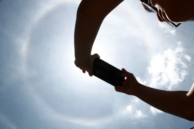 Warga merekam fenomena halo matahari menggunakan handphone, di Malang, Jawa Timur, Indonesia (27/9/2020). 