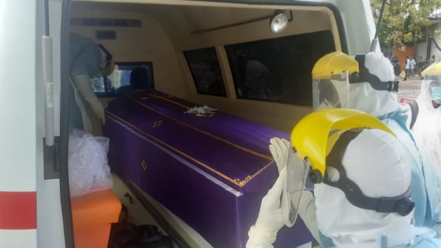 Satgas Gugus Tugas COVID-19 Kabupaten Sikka menaikan peti mayat ke atas mobil ambulance COVID-19. Foto : Istimewa.