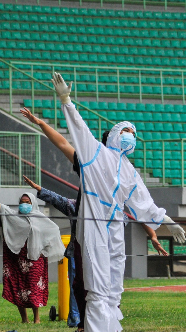 Petugas medis menggunakan APD memimpin senam pagi bersama pasien COVID-19 berstatus Orang Tanpa Gejala (OTG) di Stadion Patriot Chandrabhaga, Bekasi, Jawa Barat, Senin (28/9). Foto: Fakhri Hermansyah/ANTARA FOTO