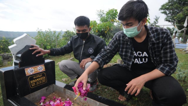 Dua anak muda dari Komunitas Sosial Jaga Palu saat tabur bunga di salah satu pemakaman massal korban bencana Pasigala di TPU Poboya, Kota Palu, Senin (28/9). Foto: Kristina Natalia/PaluPoso