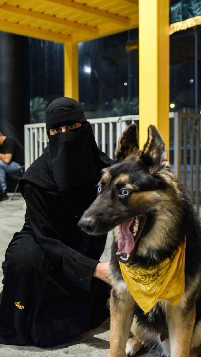 Seorang pengunjung bermain dengan anjing di kafe anjing "Barking Lot" di kota Khobar, Teluk timur Arab Saudi. Foto: FAYEZ NURELDINE/AFP