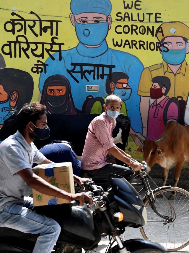 Warga melewati mural yang menggambarkan pejuang garis depan virus corona yang digambar di dinding tempat pembuangan sampah di New Delhi, India. Foto: Sajjad Hussain/AFP