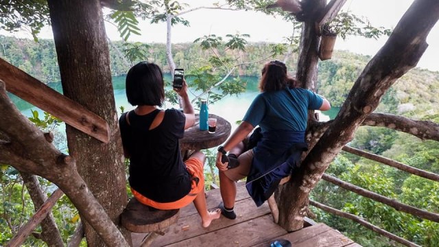 Dua pengunjung perempuan sedang menikmati pemandangan Danau Tolire dari Wisata Pulo Tareba di Ternate. Foto: Layang Sutanto/cermat