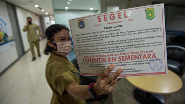 Petugas dari Pemerintah Provinsi (Pemprov) DKI Jakarta menunjukkan stiker segel yang akan dipasang pada perkantoran yang beroperasi meski ada karyawannya positif COVID-19 saat inspeksi mendadak di Senayan, Jakarta, Kamis (1/10). Foto: Aditya Pradana Putra/ANTARA FOTO
