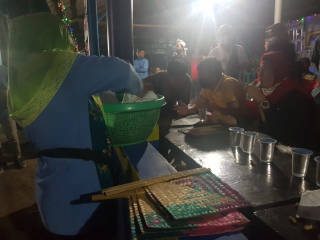 Nenek Astinih (kerudung hijau) membungkus kacang rebus pesanan Cabup Indramayu, Nina Agustina (kerudung merah) yang hadir dalam acara budaya Munjung Buyut Patu Sukra, Desa Karanganyar, Kecamatan Kandanghaur, Kabupaten Indramayu, Kamis (1/10/2020) malam. (Tomi Indra)