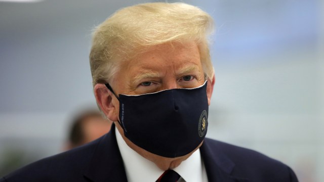 Presiden AS Donald Trump mengenakan masker saat tur di Pusat Inovasi Bioteknologi Fujifilm Diosynth, di Morrisville, North Carolina, AS, (27/7). Foto: Carlos Barria/REUTERS