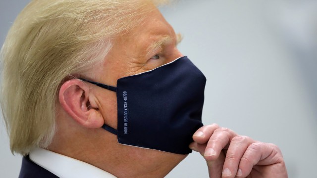 Presiden AS Donald Trump mengenakan masker saat tur di Pusat Inovasi Bioteknologi Fujifilm Diosynth, di Morrisville, North Carolina, AS, (27/7). Foto: Carlos Barria/REUTERS