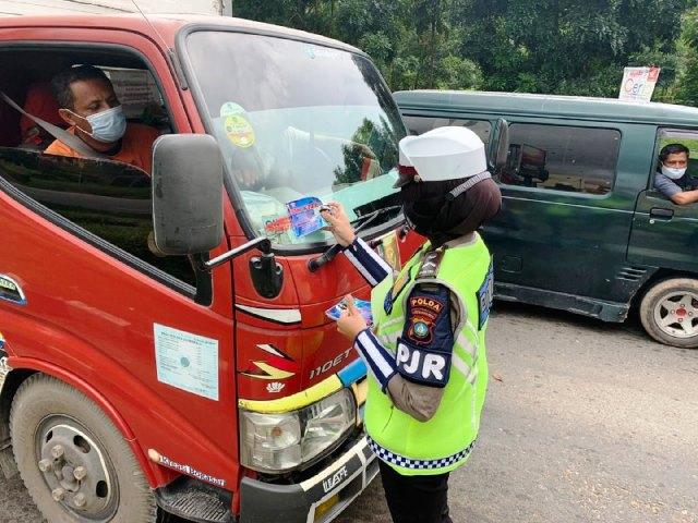 Anggota Polwan menempelkan stiker protokol kesehatan di salah kendaraan warga. (Foto: Yude/batamnews) 