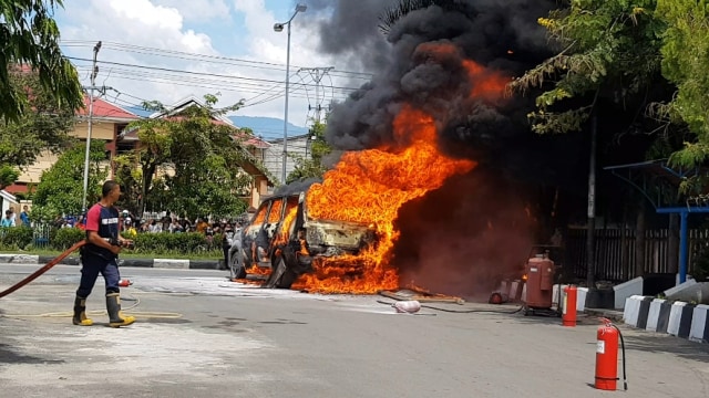 Salah satu petugas pemadam kebakaran mencoba memadamkan api pada kebakaran satu unit mobil kijang yang diduga berisikan BBM Solar, di SPBU Manimbaya, Kota Palu, Jumat (2/10). Foto: PaluPoso