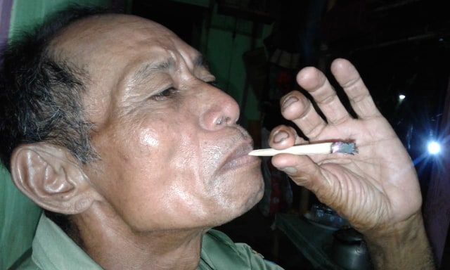 Yono, warga Desa Harjawinangun, Kecamatan Balapulang, Kabupaten Tegal menikmati rokok kretek dari kulit jagung. (Foto: Bentar)