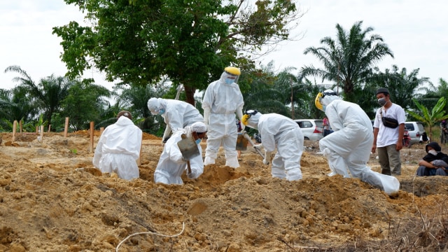 PARA penggali kubur saat bekerja menimbun tanah di kuburan pasien positif COVID-19 di TPU Tengku Mahmud, Rumbai, Pekanbaru, Sabtu (3/10/2020). 